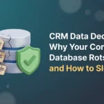 Cracked database cylinder shedding contact-card tiles on one side while a green shield with a check mark holds the other side intact, illustrating CRM data decay